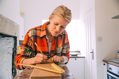 Image: Female in a kitchen with pencil and ruler